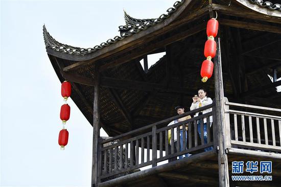  游客在重慶市武隆區(qū)黃鶯鄉(xiāng)復(fù)興村的觀景樓上欣賞田園景色（2019年3月28日攝）。 新華社記者 劉潺 攝